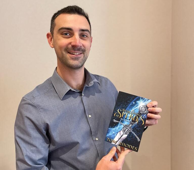 Partner Tom Rhodes with his book, The Awakening of Speros.